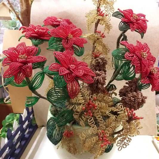 composizione floreale fioristi di stelle di Natale perline veneziane rametti dorati bacche rosse pigne marroni per idee regalo Natale centrotavola