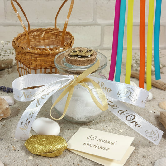 primo piano barattolino vasetto vetro tappo sughero numero 50 di anni matrimonio anniversario nozze oro confezionato confetti bianchi dorati tulle portaconfetti bigliettino altri nastrini colorati cestino packaging