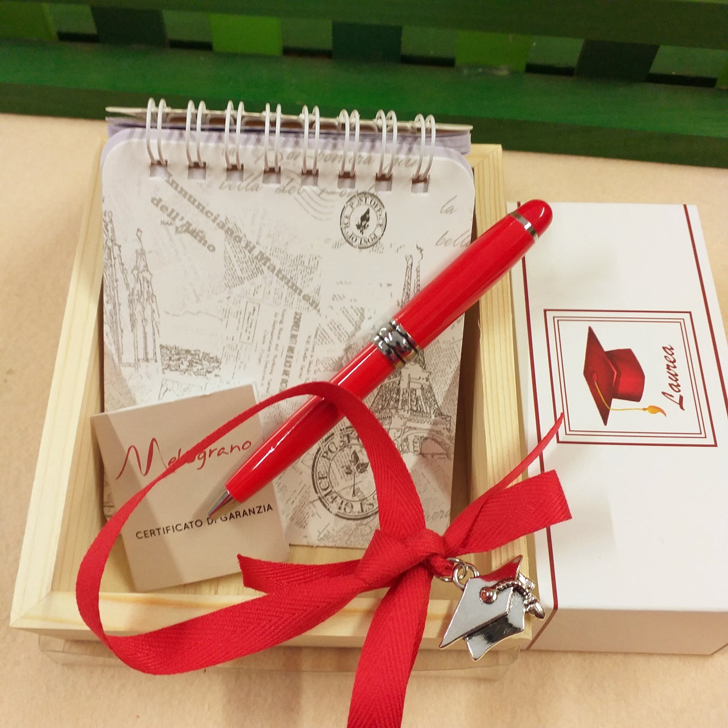 confezione con kit di scrittura bomboniera laurea block notes copertina mini penna rossa Melograno certificato di garanzia cartoncino laurea ciondolo cappello tocco astuccio di legno