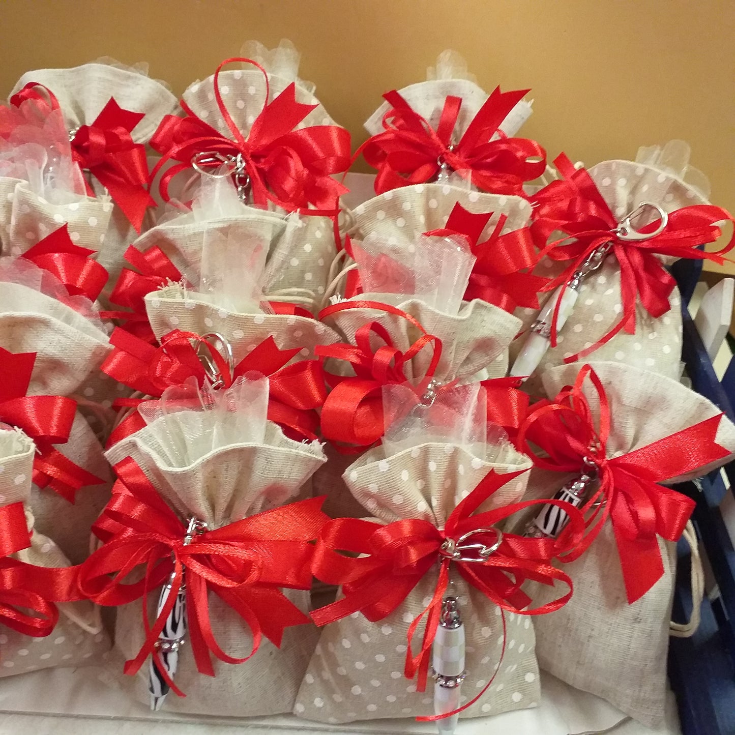 tavolinetto con sacchetti confetti rustico tela confezionato mini penna biro portachiavi bomboniera Comunione Cresima con fiocco coccarda nastro rosso