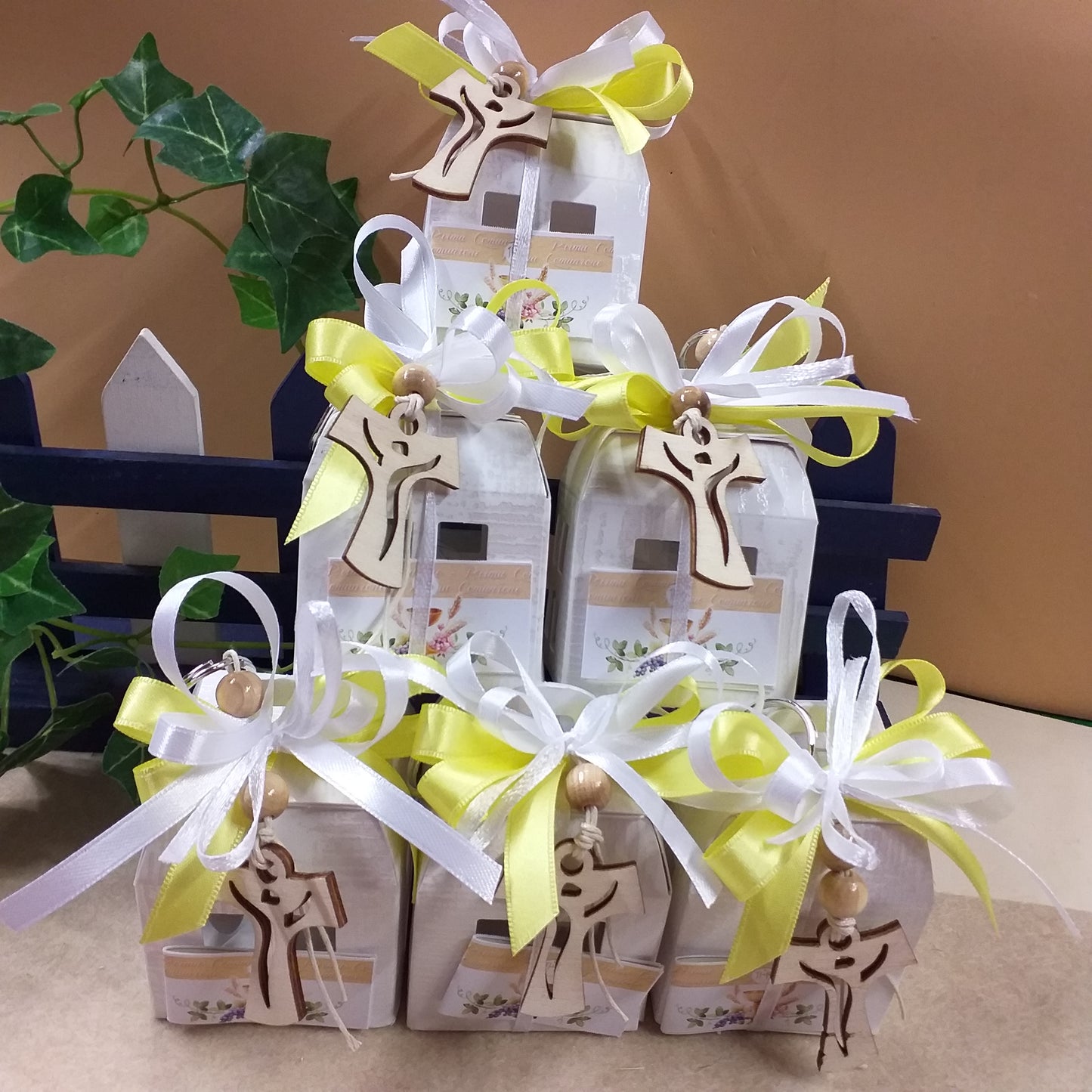 Vetrina allestimento giallo bianco bomboniere artigianali sacre religiose Comunione Cresima portachiavi Croce legno Tau francescana cordino perline confezionata confetti lanterna cartoncino scatolina bigliettino personalizzato Santo Giorno con simboli