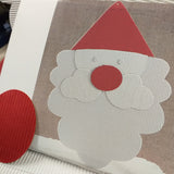 primo piano kit fai da te Babbo Natale cappello barba bianca come creare decorazioni di cartoncino con kit fustellati cartone onda bianco rosso per packaging confezionamento pacchetti regalo