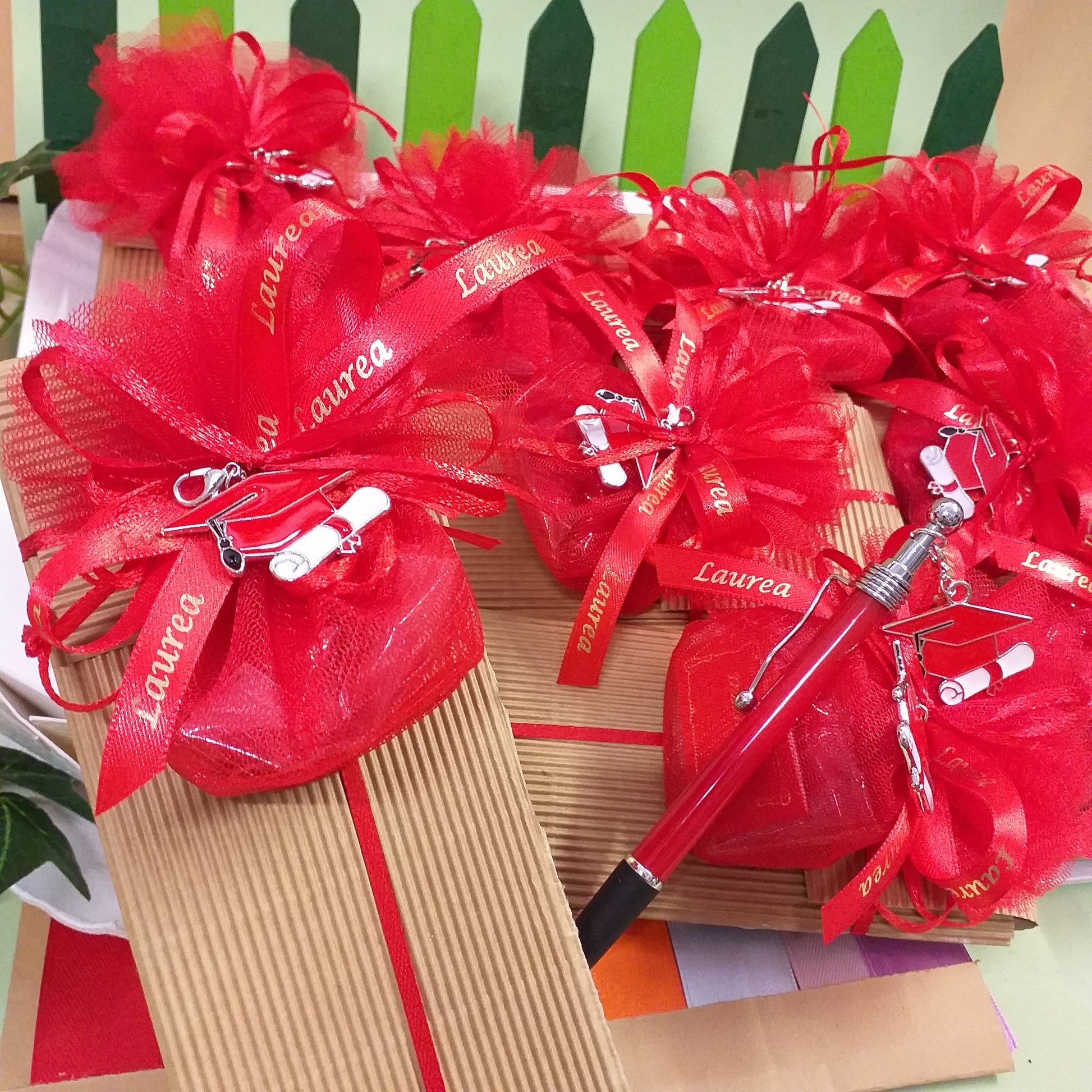 confettata festa con ricordino penna bomboniera laurea biro rossa nera ciondolo charms tocco cappello pergamena confetti rossi bigliettino sacchettino pompon tulle nastro stampato scritta scatolina astuccio confezionato packaging artigianale