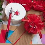 penna bomboniera laurea biro rossa nera ciondolo charms tocco cappello pergamena confetti rossi bigliettino sacchettino pompon tulle nastro stampato scritta scatolina astuccio confezionato packaging artigianale bustina di cartoncino ondulato avana beige colori nastrini